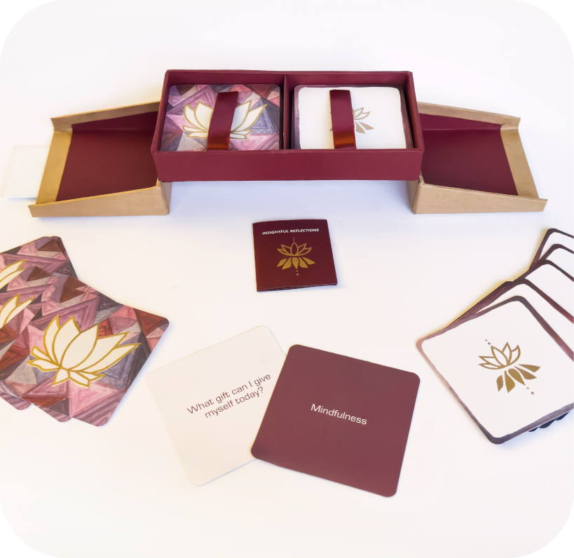 Top-down view of the Insightful Reflections box opened with six cards displayed face-up below it. The cards read: 'Love', 'Balance', 'Gratitude', 'How have I created this?', 'What is important to remember today?', and 'Who would I be if I accepted this?'.